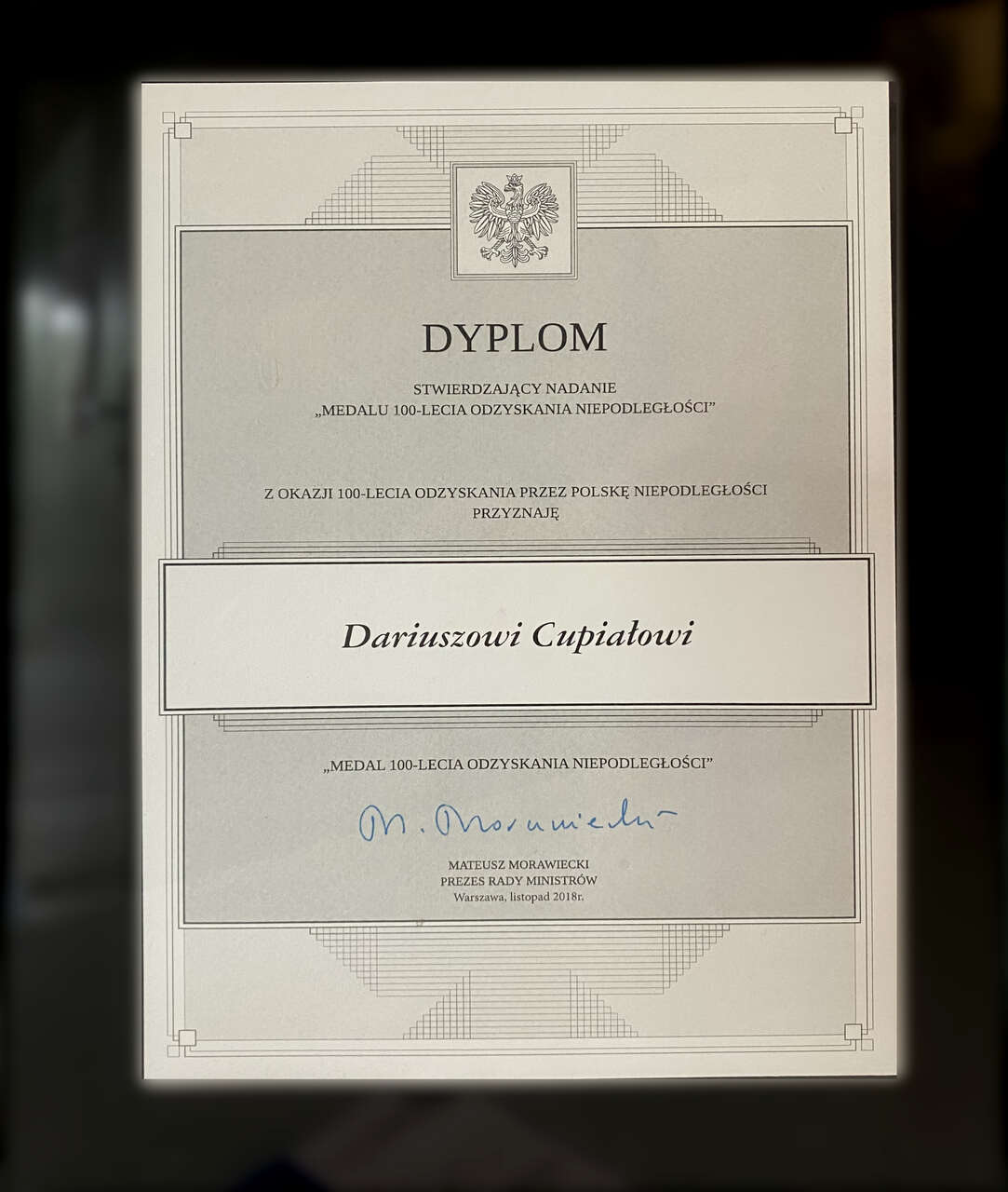 Dyplom nadania „Medalu 100-lecia Odzyskania Niepodległości” Dariuszowi Cupiałowi. Państwowe odznaczenie przyznane w listopadzie 2018 roku przez Premiera RP Mateusza Morawieckiego z okazji wyjątkowego, narodowego jubileuszu stulecia niepodległości Polski.